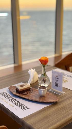 a table with a plate with a cake and a vase of flowers at SEAVIEW HOTEL in Umm Lujj