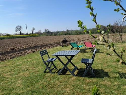 trois chaises et une table de pique-nique devant un champ dans l'établissement Chez Ophélie et Gaël, à Saint-Malo