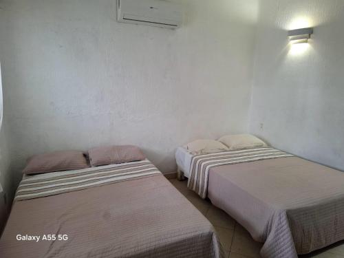 two beds in a room with white walls at Casa y Villa Diamante, Manzanillo in Manzanillo