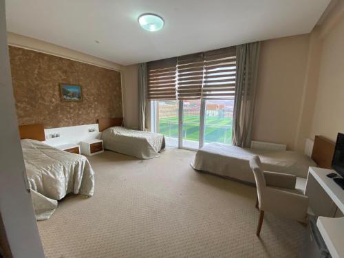 a bedroom with two beds and a large window at Arena Hotel Dashkasan in Xoşbulaq