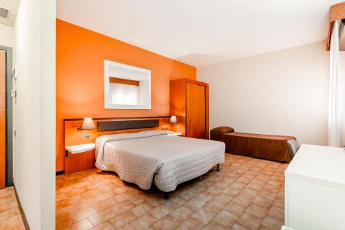 a hotel room with a bed and orange walls at RHI Porta Bologna in Pieve di Cento
