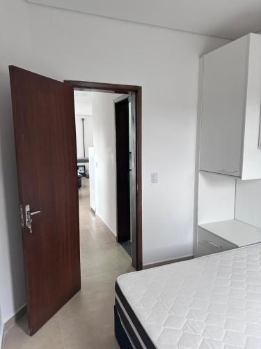 a bedroom with a bed and a open door at Casa com piscina em Peruíbe in Peruíbe
