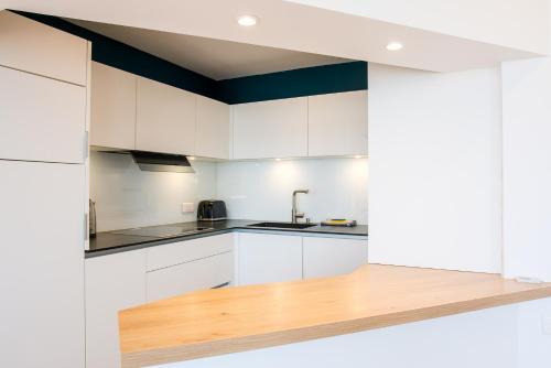 a kitchen with white cabinets and a wooden counter top at Appartement sainte marine vue mer in Combrit