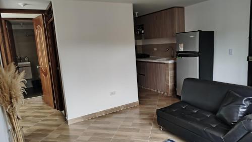 a living room with a black couch and a kitchen at DESTINY Apto villas del Río in San Rafael