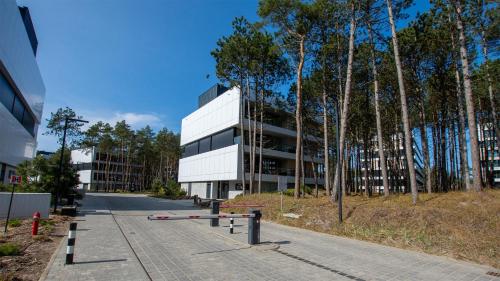 a white building with trees in front of it at VacationClub - Shellter Rogowo Apartament 6 in Rogowo