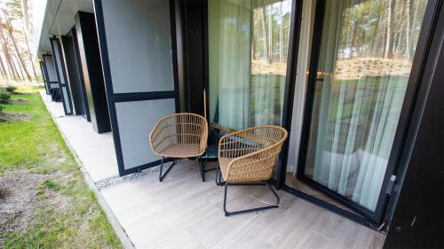 two chairs sitting on the porch of a house at VacationClub - Shellter Rogowo Apartament 6 in Rogowo