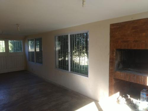 La Estanciaにあるcasa de campo a metros del lagoの暖炉と窓のある空のリビングルーム