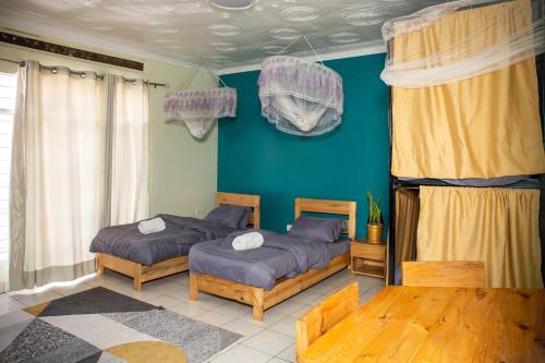 two beds in a room with blue walls at Tugende Hostel in Kigali