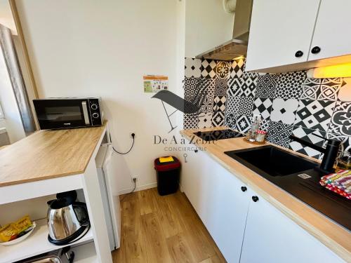 a small kitchen with a sink and a microwave at L'Authentique - Situé en face des thermes et tout proche du coeur de ville in Rochefort