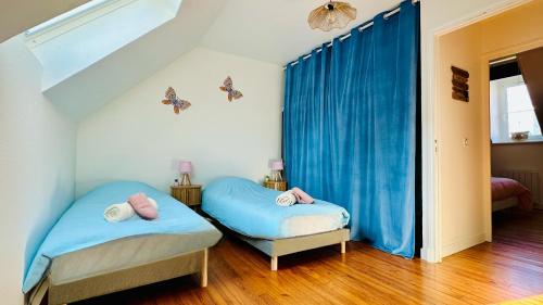 two beds in a room with blue curtains at Chez Mag maison de pêcheur proche plage in Ault