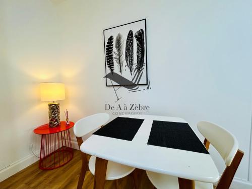 a dining room with a white table and chairs at L'Authentique - Situé en face des thermes et tout proche du coeur de ville in Rochefort