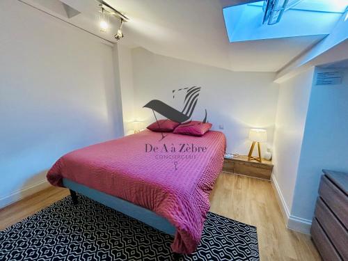 a bedroom with a pink bed with a chair on it at L'Authentique - Situé en face des thermes et tout proche du coeur de ville in Rochefort