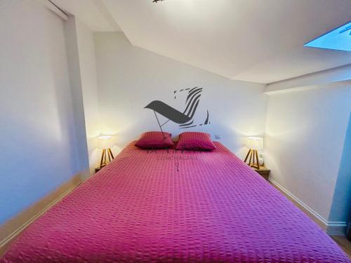 a bedroom with a pink bed with two pink pillows at L'Authentique - Situé en face des thermes et tout proche du coeur de ville in Rochefort