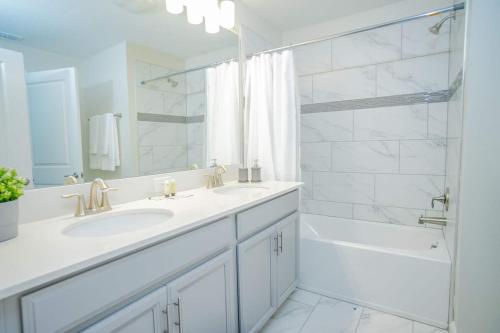 Un baño blanco con lavabo y ducha. en Relax In Ultimate Comfort With Pool & Bbq Area, en Kissimmee