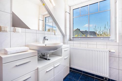 a white bathroom with a sink and a window at Ferienwohnung 2 in Groß Zicker