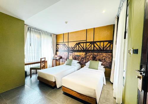 a hotel room with two beds and a table at U Inchantree Kanchanaburi in Kanchanaburi