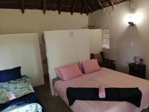 Un dormitorio con una cama con almohadas rosas. en BEAL Cultural Village, en Hammanskraal