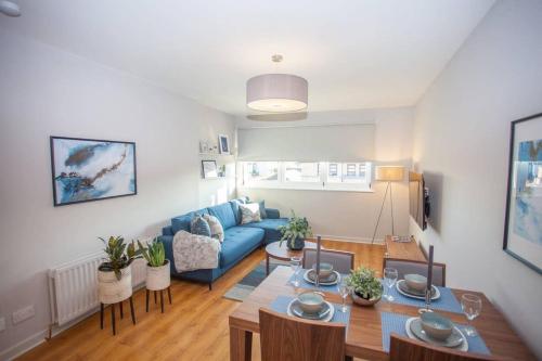 a living room with a blue couch and a table at Stylish 2-Bed Apartment Near Glasgow Green in Glasgow