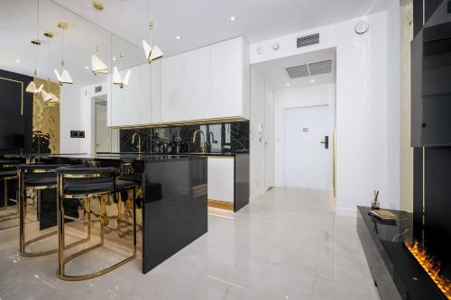 a kitchen with white cabinets and black counter tops at Goldstar Apartament- Wanna z widokiem, 19 Piętro, Hanza Tower Szczecin in Szczecin