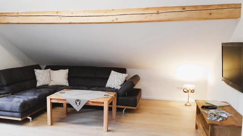 a living room with a black couch and a table at FeWo "Im Städt´le" Immenstadt in Immenstadt im Allgäu