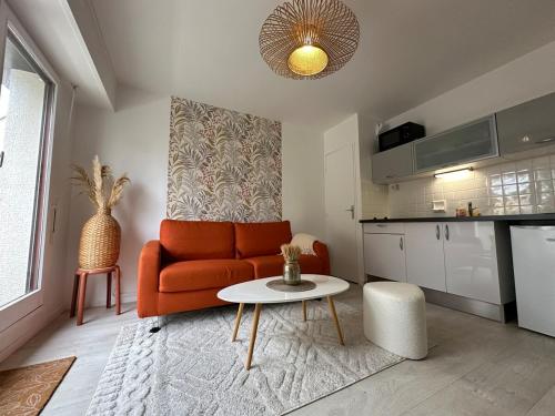un salon avec un canapé orange et une table dans l'établissement Cocon proche du centre ville - balcon - parking, à Vannes