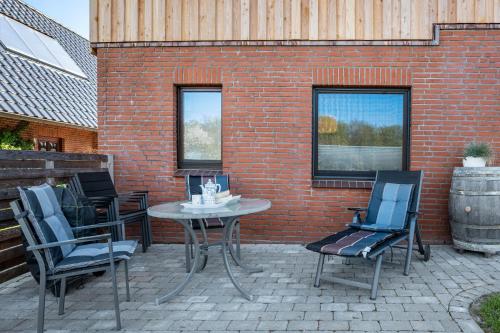 a patio with a table and chairs and a brick wall at Küstenkind in Westerholz