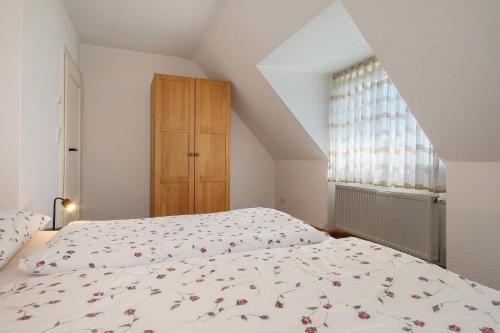a bedroom with a bed with a floral bedspread and a window at Obst- und Ferienhof Lehle in Immenstaad am Bodensee