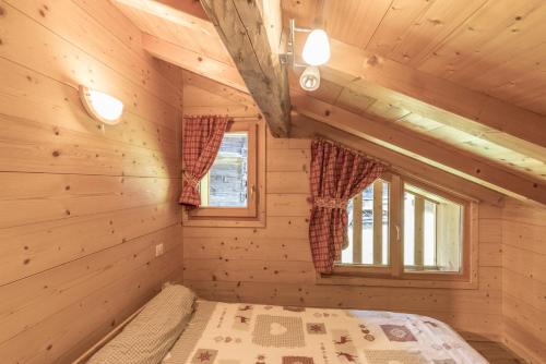 a bedroom in a log cabin with a bed and two windows at Les Salamanes - Chalet 6-7 pers in Sixt