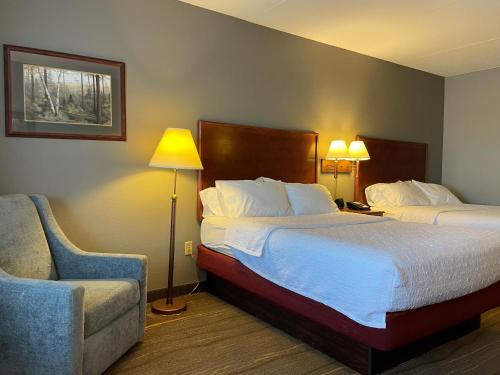 a hotel room with two beds and a chair at SouthShore Hotel on Lake Bemidji, Trademark Coll by Wyndham in Bemidji
