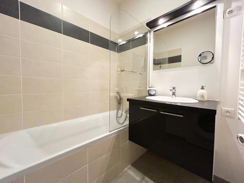 une salle de bain avec un lavabo, une baignoire et un miroir dans l'établissement Appartement Bordeaux centre, à Bordeaux