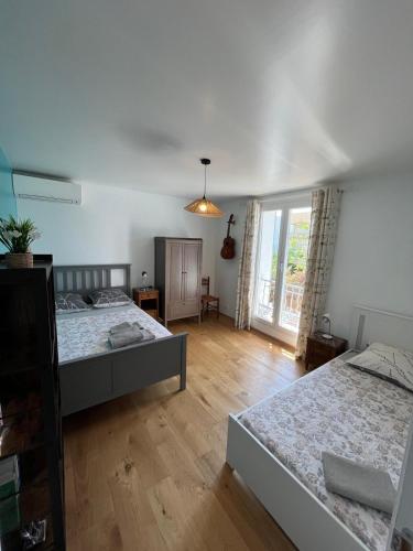 une chambre avec deux lits et une grande fenêtre dans l'établissement Villa la Désirée ,haut de la villa, entièrement rénovée, 4 étoiles, climatisé, parking privé et 120m2 de jardin, à Antibes