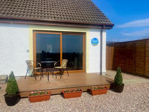 a wooden deck with a table and chairs on it at Dalchalm Hideaway in Brora