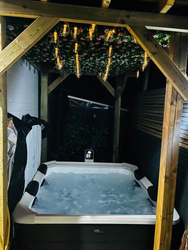 a jacuzzi tub sitting under a wooden structure at Luxe 1B Chalet, HotTub, free parking Nr LTN Airport, L&D Hosp, Whipsnade Zoo, fast trains into Central London in Luton