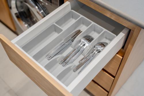 a white drawer with cutlery in a kitchen at Luxury 1BR Apartment near Muweilah Sharjah - Sunny Side up in Sharjah Intl