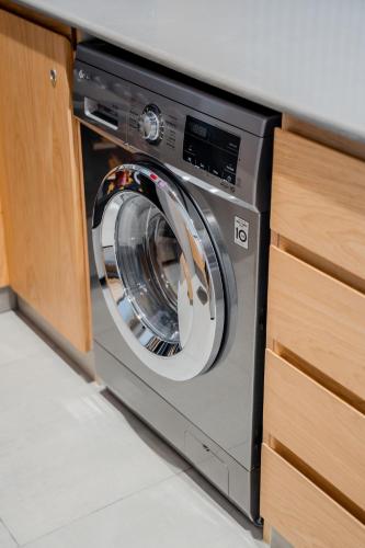 a washing machine sitting in a cabinet in a kitchen at Luxury 1BR Apartment near Muweilah Sharjah - Sunny Side up in Sharjah Intl