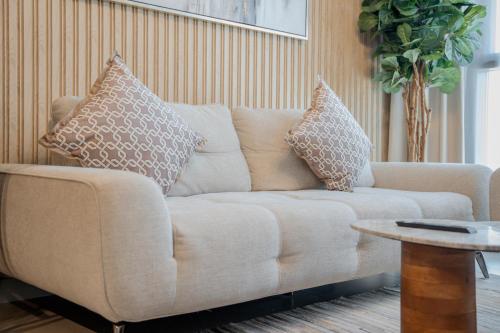a couch in a living room with pillows on it at Luxury 1BR Apartment near Muweilah Sharjah - Sunny Side up in Sharjah Intl