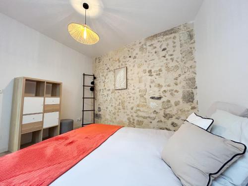 une chambre avec un lit blanc et un mur en pierre dans l'établissement Appartement Bordeaux centre, à Bordeaux