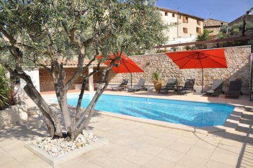 une piscine avec un arbre et deux parasols à côté dans l'établissement Les Terrasses de la Roque-Alric, à La Roque-Alric