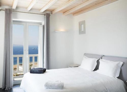 une chambre blanche avec un lit et une grande fenêtre dans l'établissement Exquisite Mykonos Villa Villa Exclusive 3 Bedroom Private Pool, à Mykonos