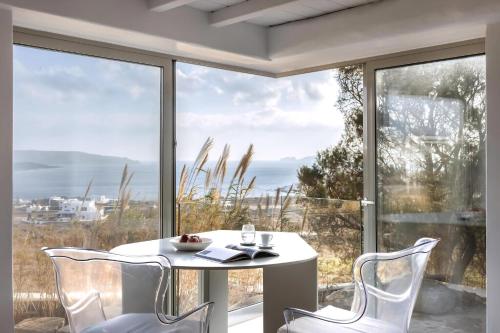 a white table and chairs in front of a large window at Spectacular Kalafatis Villa 1 Bedroom Villa Vibhu Private Jacuzzis & Infinity Pool in Kalafatis