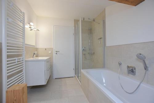 a bathroom with a tub and a shower and a sink at "Löwenzahn", Oberstaufen-Wiedemannsdorf in Oberstaufen