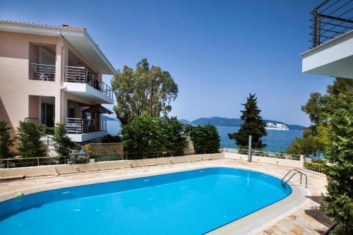 a swimming pool in front of a building with a view of the water at Deluxe Kefalonia Apartment Apartment Amaryllis 1 Bedroom Outdoor Pool Karavomilos in Karavomylos