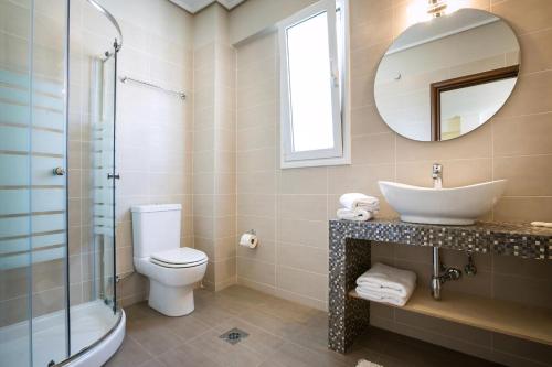 a bathroom with a sink and a toilet and a mirror at Deluxe Kefalonia Apartment Apartment Amaryllis 1 Bedroom Outdoor Pool Karavomilos in Karavomylos