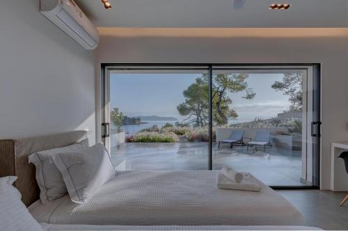 a bedroom with a bed and a view of the water at Super Luxury Skiathos Villa Seven Stunning Bedroom Suites Villa Levanta Achliades in Achladies