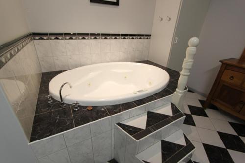 La salle de bains est pourvue d'une baignoire et de carrelage. dans l'établissement Lazy River Motor Inn, à Swan Hill