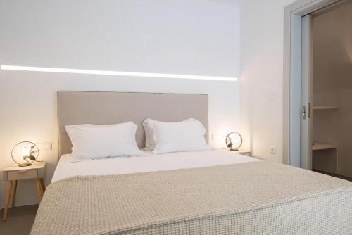 a white bedroom with a large bed with white pillows at Beautiful Paros Villa 1 Bedroom The Calming Villa Wonderful Sea Views & Jacuzzi Naousa in Livadia