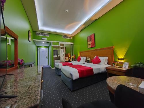 a hotel room with two beds and green walls at Le Paradise Palace Hotel Deira Dubai Al Rigga in Dubai