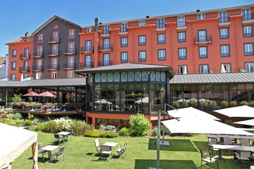 un hôtel avec des tables et des chaises devant un bâtiment dans l'établissement Le Grand Hotel & Spa, à Gérardmer