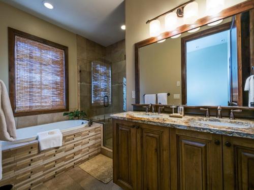 een badkamer met een bad en een grote spiegel bij Fairway Springs by Park City Vacations in Park West Ski Area Heliport