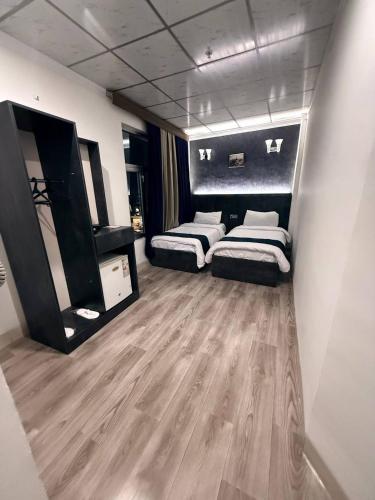 two beds in a room with wooden floors at Vote Hotel 1 in Erbil